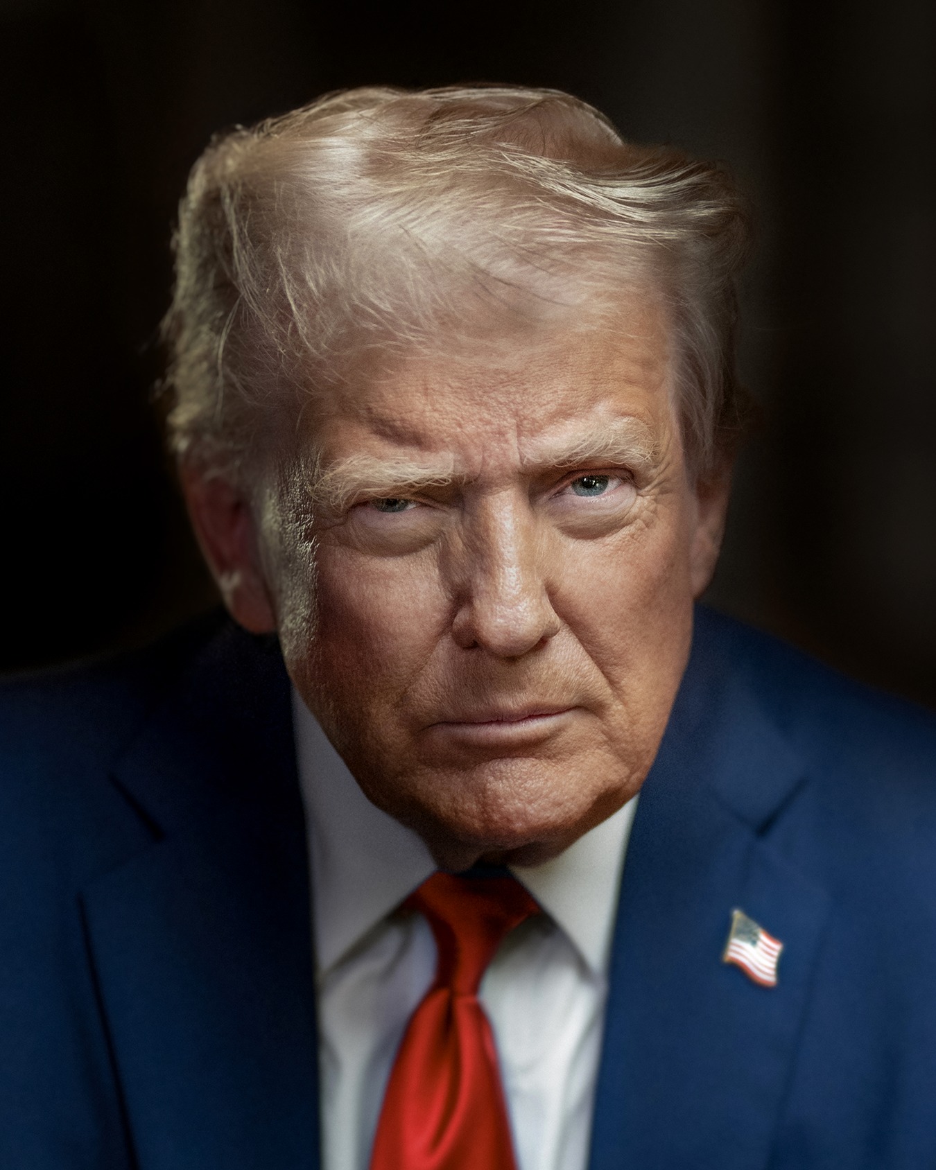 Donald Trump in a blue jacket, white shirt, red tie and American flag pin, in an official portrait against a dark background.